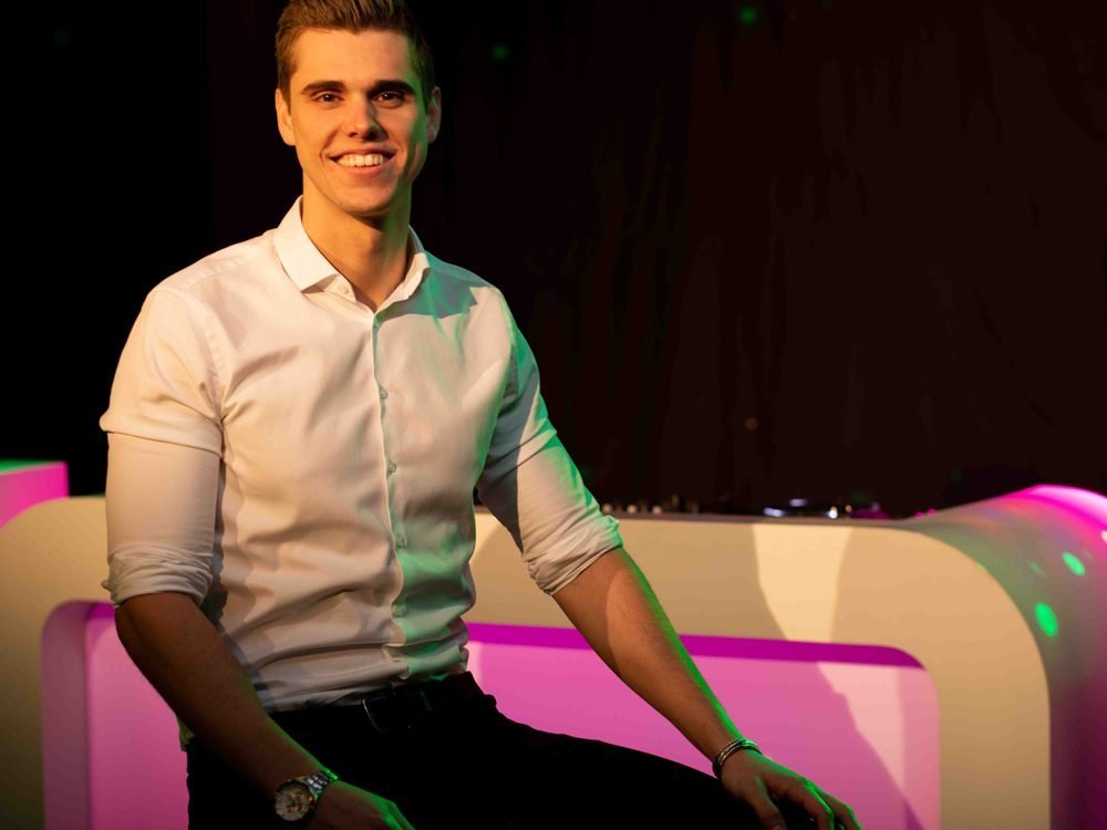 DJ Barry poseert glimlachend voor zijn verlichte DJ booth
